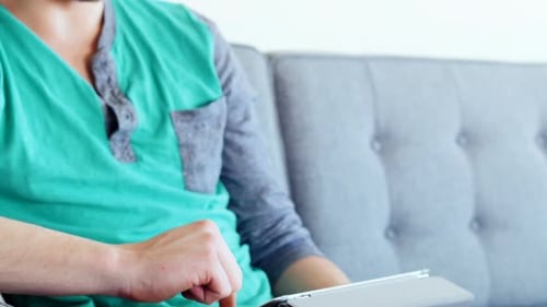 Man Using Tablet on Couch Indoors