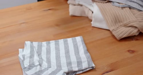 Arm Folding Clothes on Wooden Table Indoors