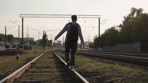 Mann geht entlang der Bahngleise und hebt seine Hände hoch und fühlt sich frei