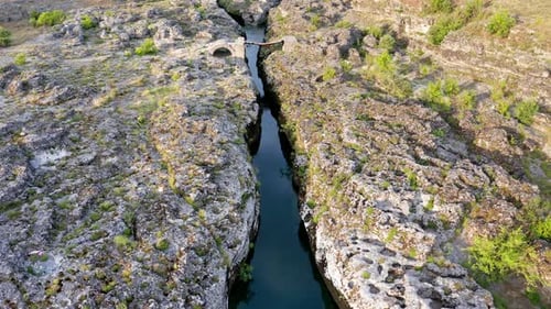 Narrow mountain river flowing through rocky landscape, Stream bed cut deep into stones