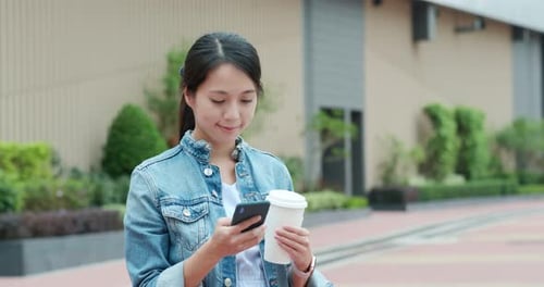 Woman Using Phone and Holding Drink Outside
