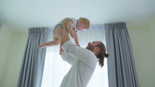 Loving Father Holding Smiling Baby in the Air