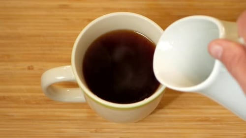 Adding Milk to Steaming Cup of Dark Tea