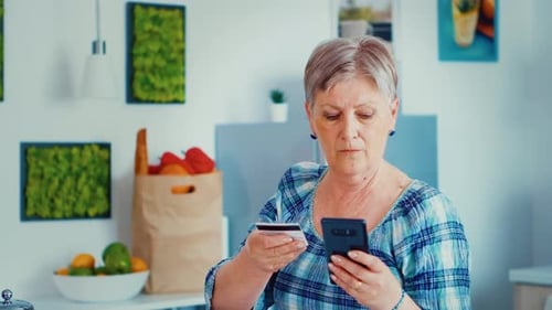 Senior Woman Using Smartphone with Credit Card