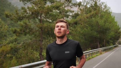 Athletic muscular triathlete running on mountain road