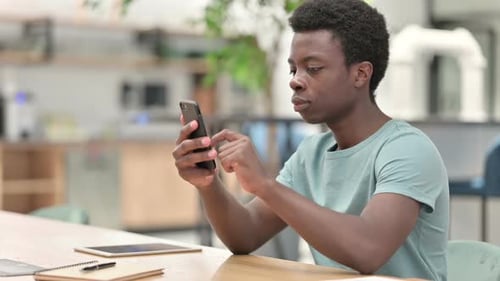 Young Adult Using Smartphone at Desk Indoors