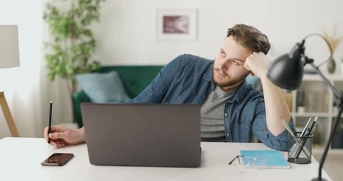 Nachdenklicher Mann mit Laptop zu Hause