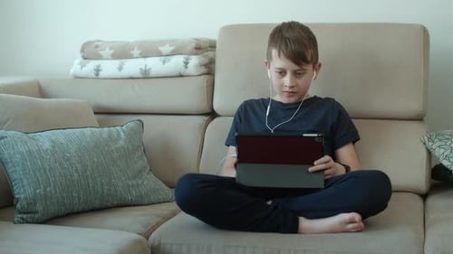 Boy of 8 years old studies lessons on a tablet. Distance education or online school