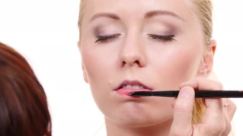 Maskenbildner trägt Lipgloss auf Modellippen auf