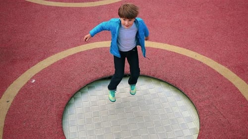 Un niño saltando en el trampolín en el patio de recreo