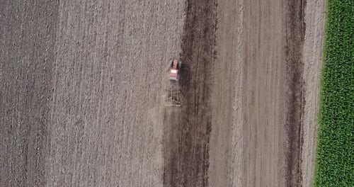 Farm Tractor Working And Tilling The Soil At The Field. aerial top-down