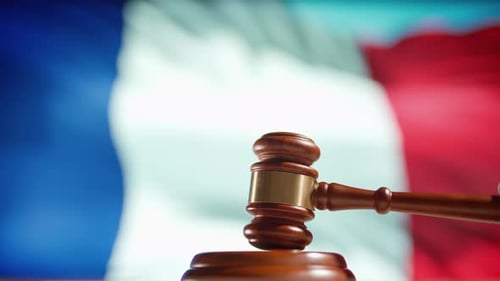 Um martelo de juiz com uma bandeira da França em segundo plano