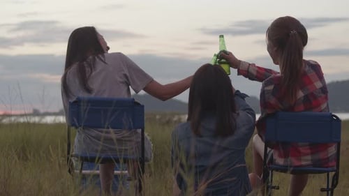 Three Friends Enjoy Sunset Drinks in Rural Field