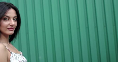 Beautiful Woman Posing in Front of Green Wall