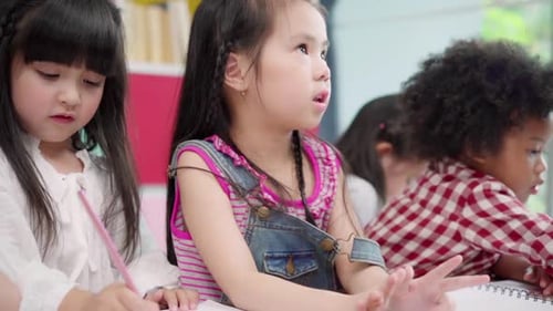 Multi-ethnic young boys and girls happy funny study and play painting on paper at elementary school.