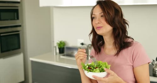 Woman Eating Fresh Salad in Modern Kitchen