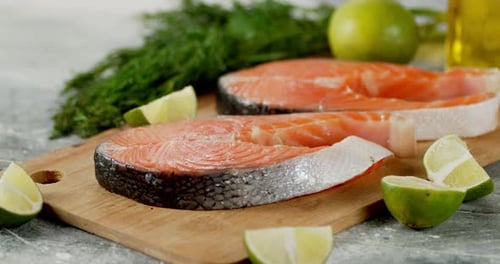 Rohe Lachsstücke mit Limettenstücken rotieren auf dem Tisch