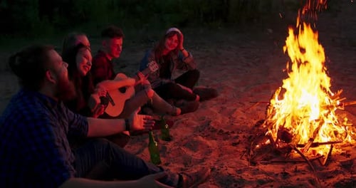 Friends Sing at Campfire on Sandy Beach at Night