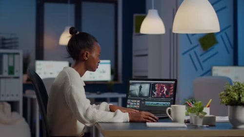 Woman Video Editing at Desk in Office at Night