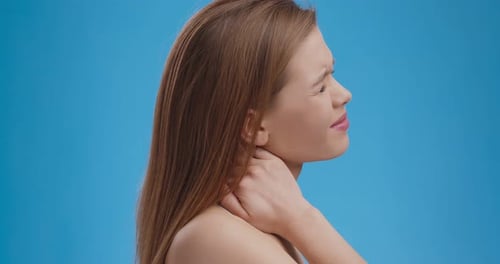 Neck Pain. Tired Woman Suffering with Painful Feelings in Neck Muscles, Blue Studio Background