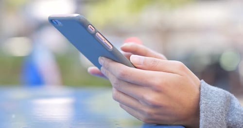 Woman's hands scrolling on smartphone device outdoors