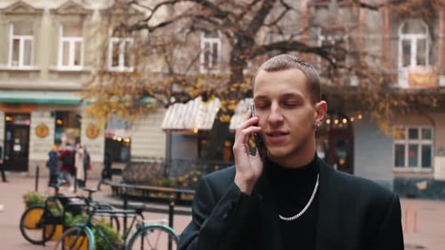 Mann ruft Telefon im Freien an. Stilvoller Startupper spricht draußen mit Handy. Sprachnachricht. Portrait