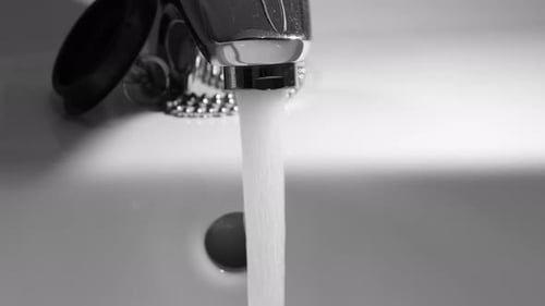 Water Runs From Faucet Into Sink In Monochrome