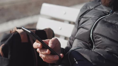 Person Uses Smart Phone on Urban Bench