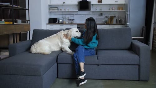 Woman Cuddling Golden Retriever Dog on Sofa
