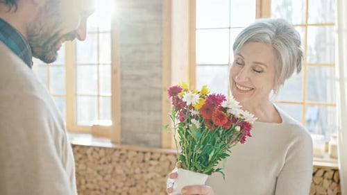 Young Man Presents Bouquet to Smiling Woman