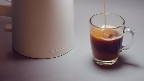 Milk Pouring Into Coffee Cup by Kettle