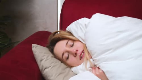 Une jeune femme endormie épuisée tombe sur le canapé, une fille malade atteinte de Covid ou de grippe