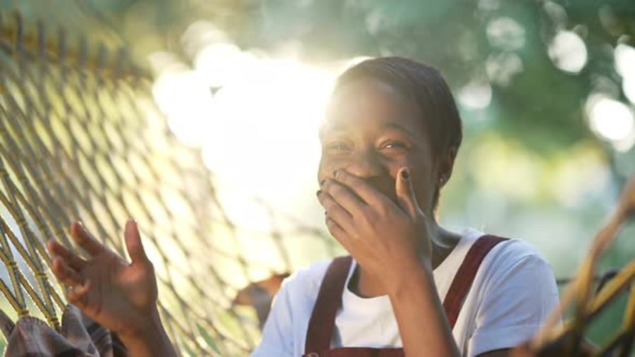 Cover for Cheerful African American Woman Laughing Looking at Camera Gesturing Sitting in Sunrays Outdoors