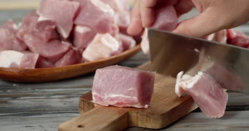 Butcher Cuts Raw Pork on Cutting Board