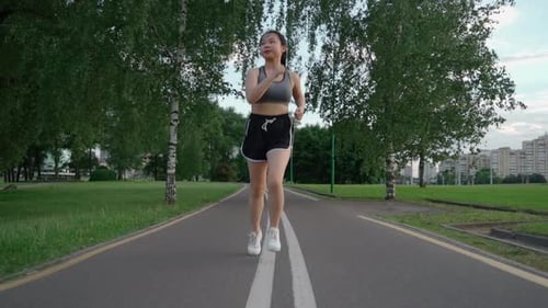 Asian Young Beautiful Woman Running for Health in the Evening Sunset on Street in Public Park