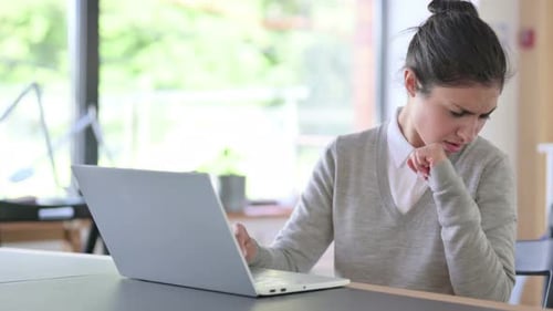 Woman Coughs While Working on Laptop Indoors