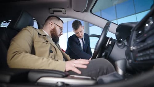 an Adult Man Sits in the Salon of a New Car in a Dealership