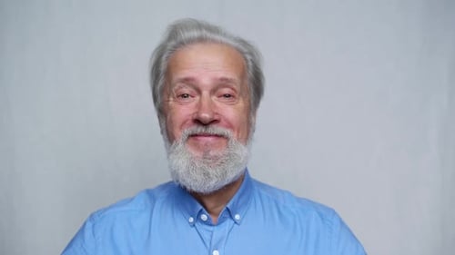 Closeup Studio Portrait of Cheerful Grayhaired Mature Man Smiling Looking at Camera on White