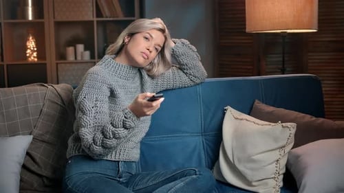 Indifference Woman in Warm Sweater Watching Television Set Switching Channels with Remote Control