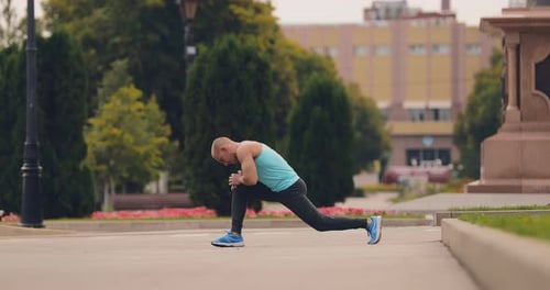 Young Athlete Stretches the Muscles of the Legs Warm Up on the Street