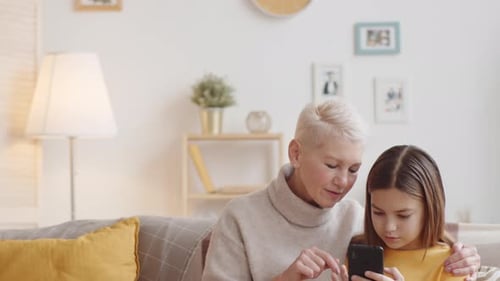 Grandmother and Granddaughter Using Smartphone Together at Home