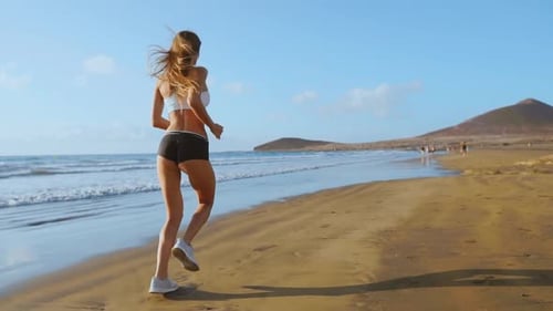 Beautiful Sporty Women in White Sneakers Running Along a Beautiful Sandy Beach, Healthy Lifestyle