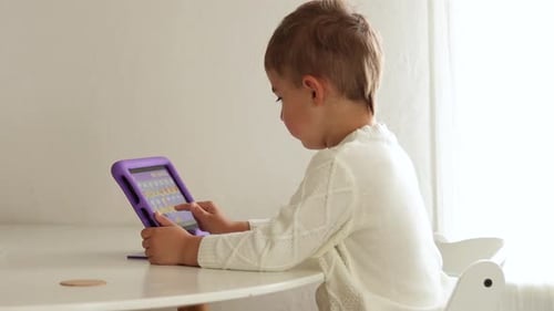 Child Uses Tablet at Table in Bright Home