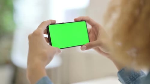 Rear View of African Woman Watching Smartphone with Green Chroma Key Screen