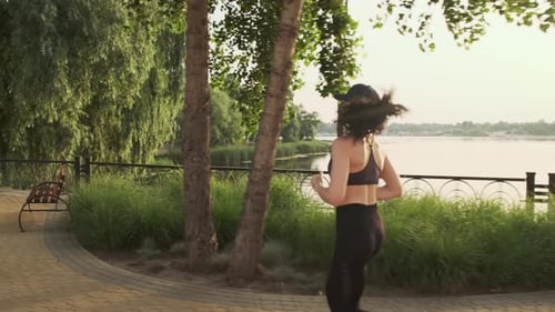 Woman Running Training Intense Cardio Workout in City Park Against the Sun