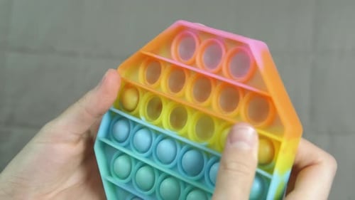 Hands Push Dimples in Colorful Geometric Toy