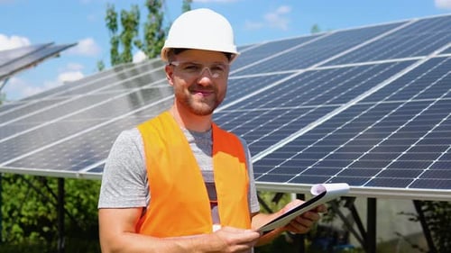 Man Inspecting Solar Panels With Clipboard Smiling