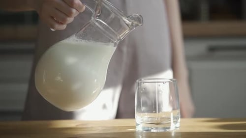Woman Pours Milk From Pitcher Into Glass