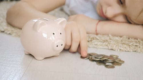 Little girl blond put coins in a piggy bank. Saving money concept