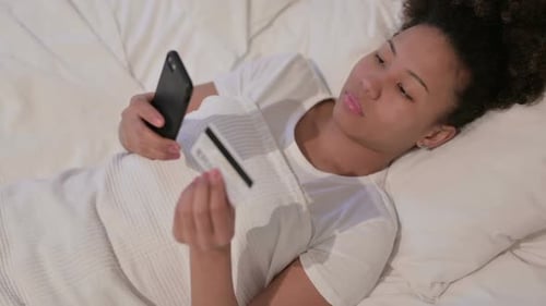 African Woman with Online Payment Failure on Smartphone in Bed